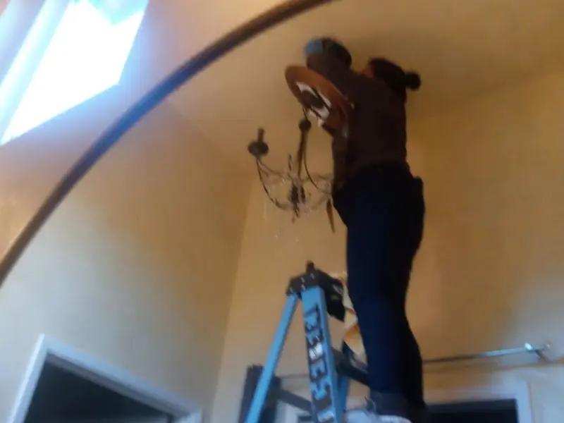 Electrician installing a chandelier in a Berwick residence